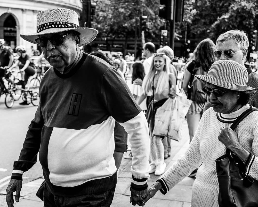 London street photography - Man holding woman's hand by Adrian Crook